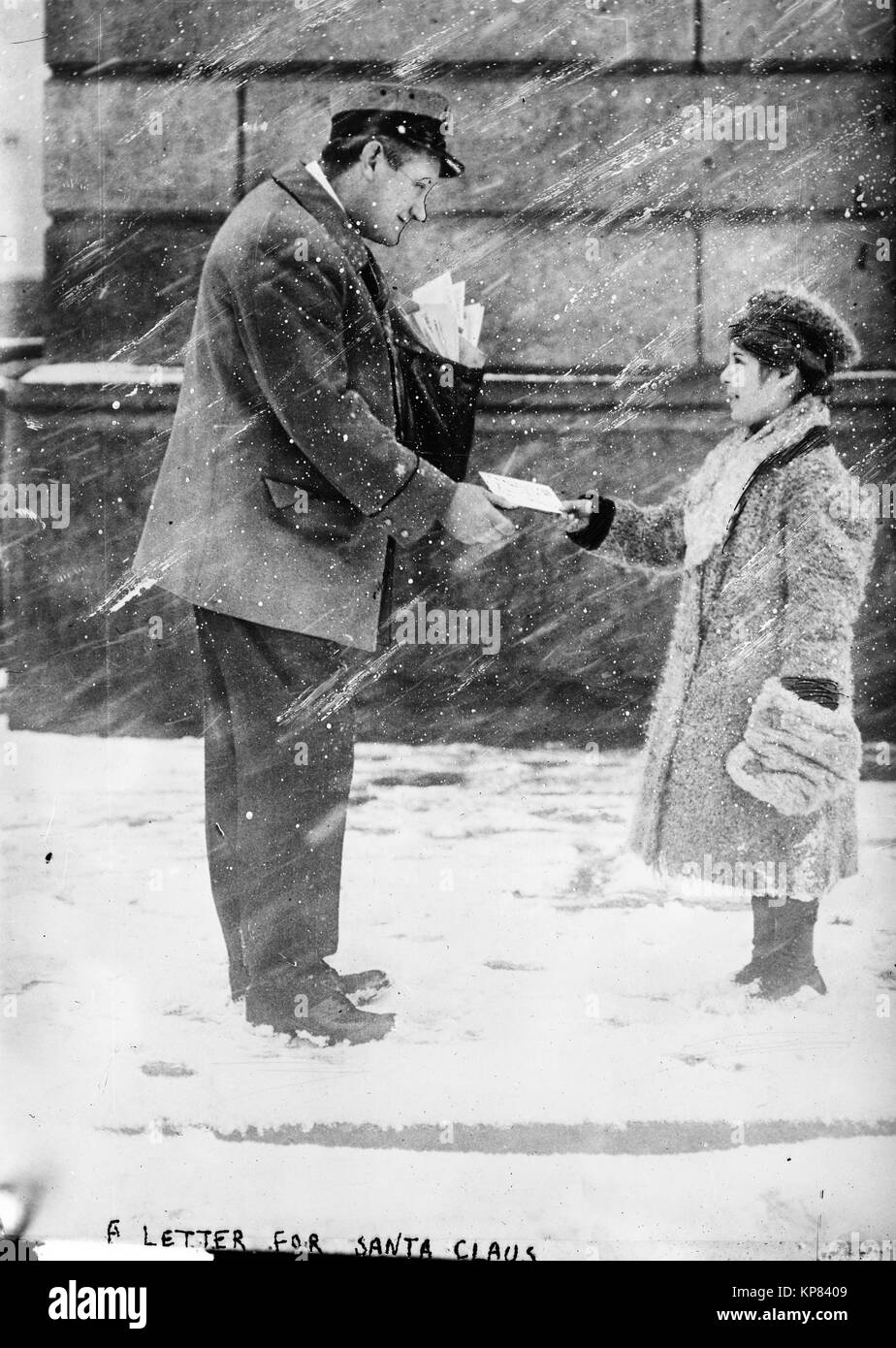 boy giving mailman a letter for Santa Claus in early 1900s, early 20th century while standing in the snow Stock Photo