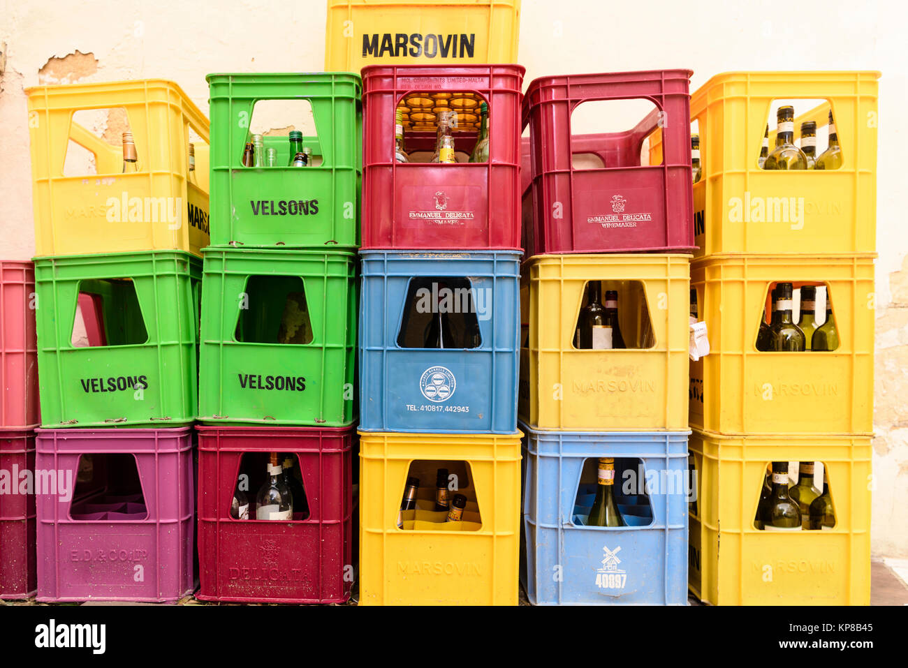 Multicoloured crates with empty glass bottles awaiting collection outside a bar for recycling. Stock Photo