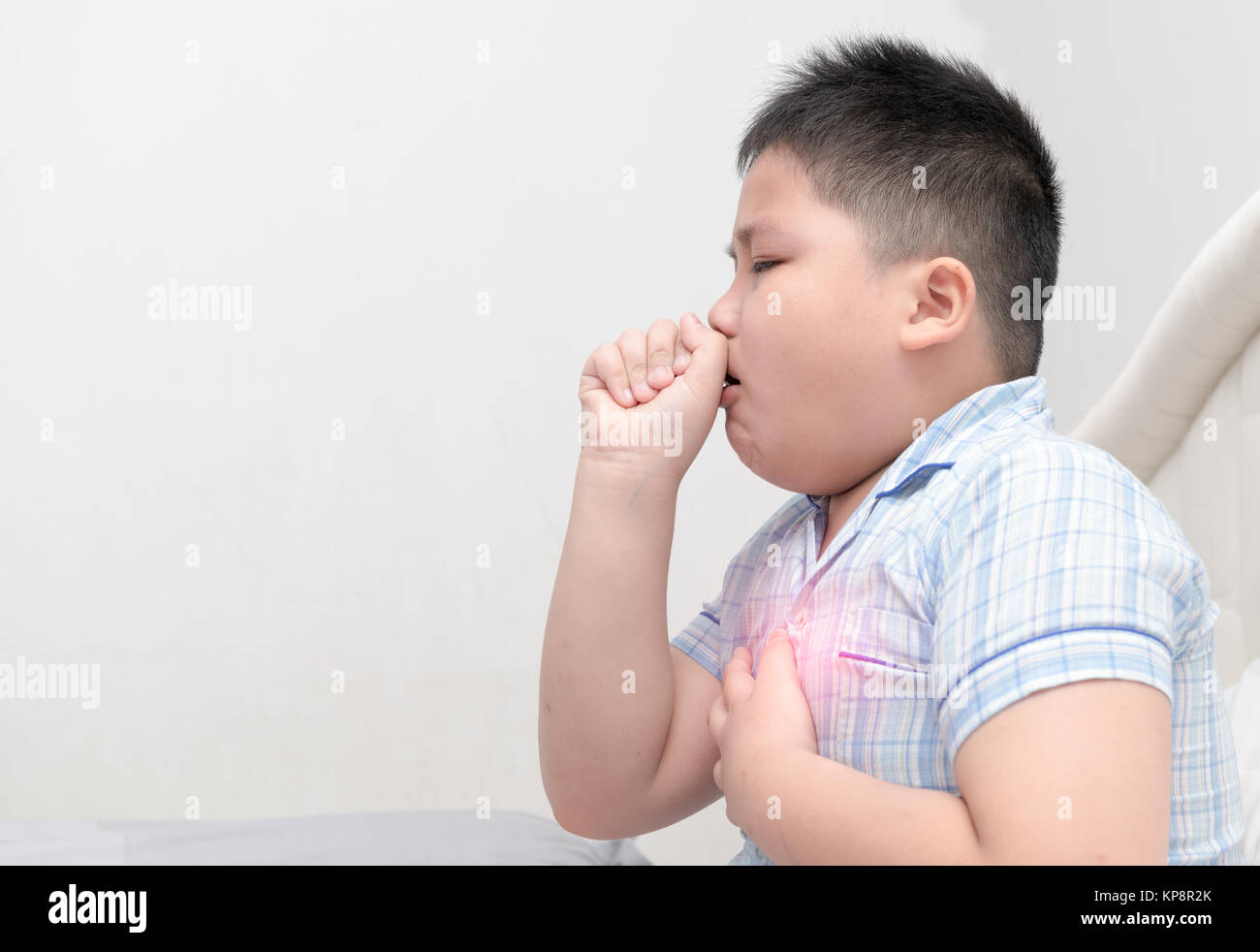 Sick obese boy is coughing and throat infection on bed, health care concept Stock Photo