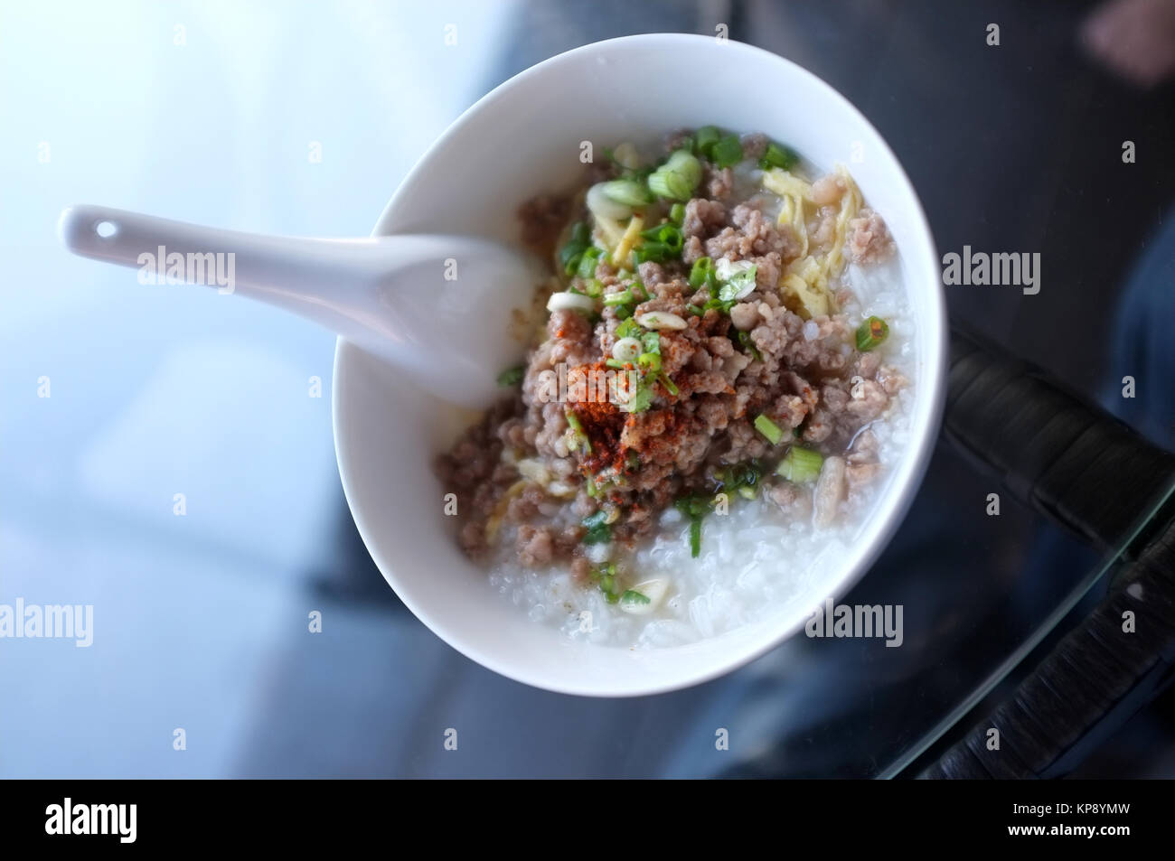 Soft boiled rice with mince pork, Congee in white bowl isolated on black background Stock Photo