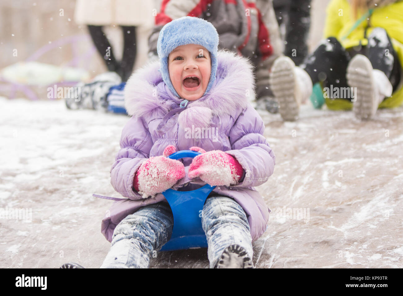 Five-year girl with a happy cry slipping ice slides Stock Photo