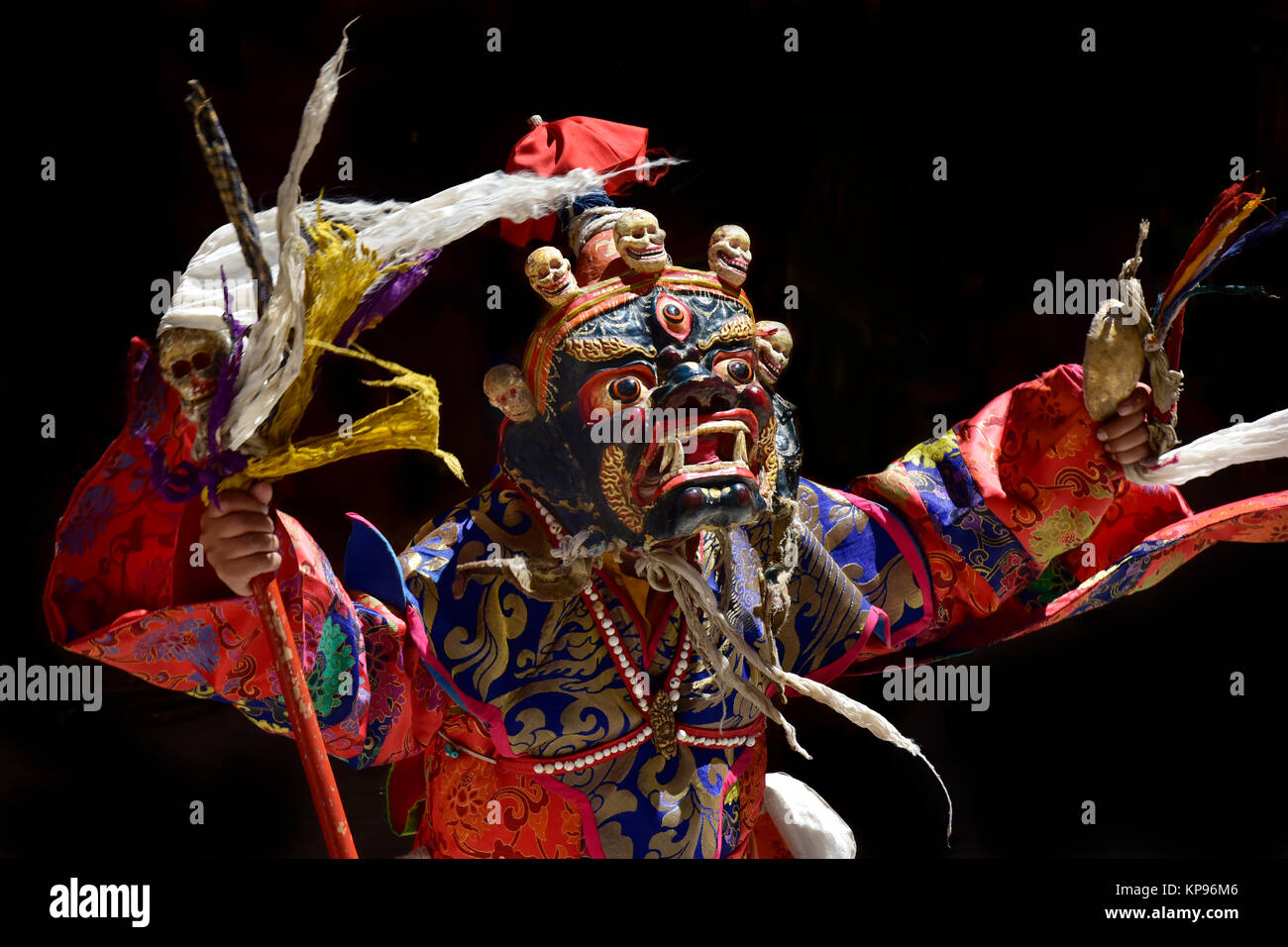 Ancient Tibetan sacral mask Palden Lhamo: a blue mask with small human skulls, bright red flags at the top, a wand in hand, the Himalayas. Stock Photo