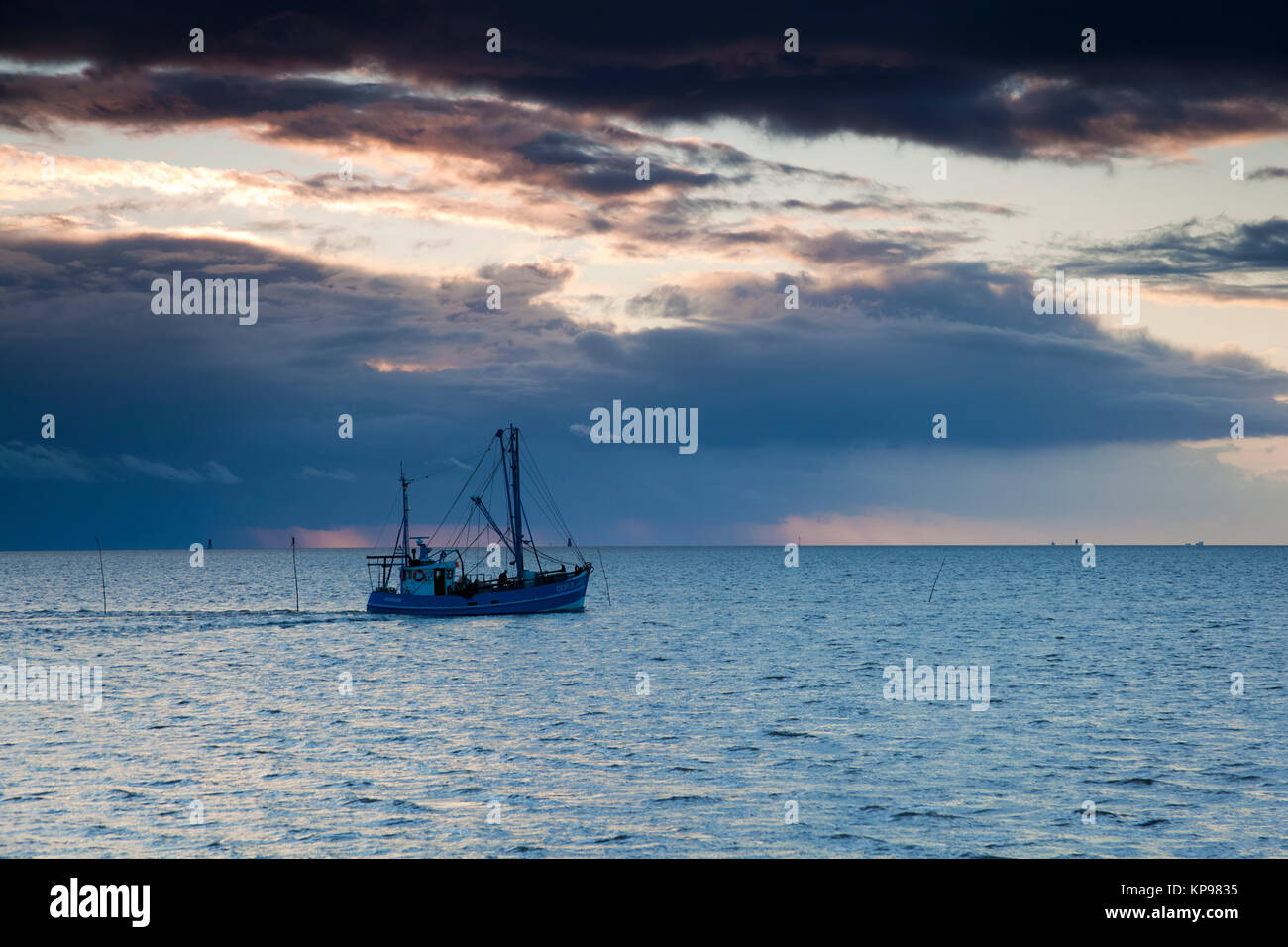 letztes Licht am Meer, warme Sonnenstrahlen und Wellen am Meer, Wattenmeer oder das Licht bei wenig Wasser, Spiegelung der Wolken im Wattenmeer Stock Photo