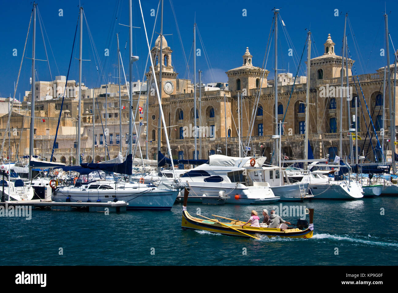 A traditional Maltese Lazzu fishing boat passing the Maritime Museum and marina at Vittoriosa in Valletta on the Mediterranian Island of Malta Stock Photo