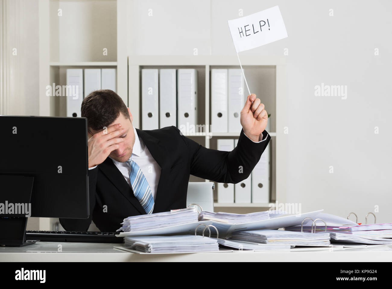 Overworked Accountant Holding Help Sign At Desk Stock Photo