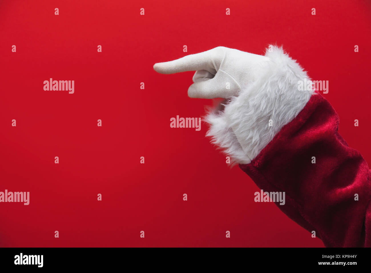 Santa Claus hand pointing finger against a red background Stock Photo