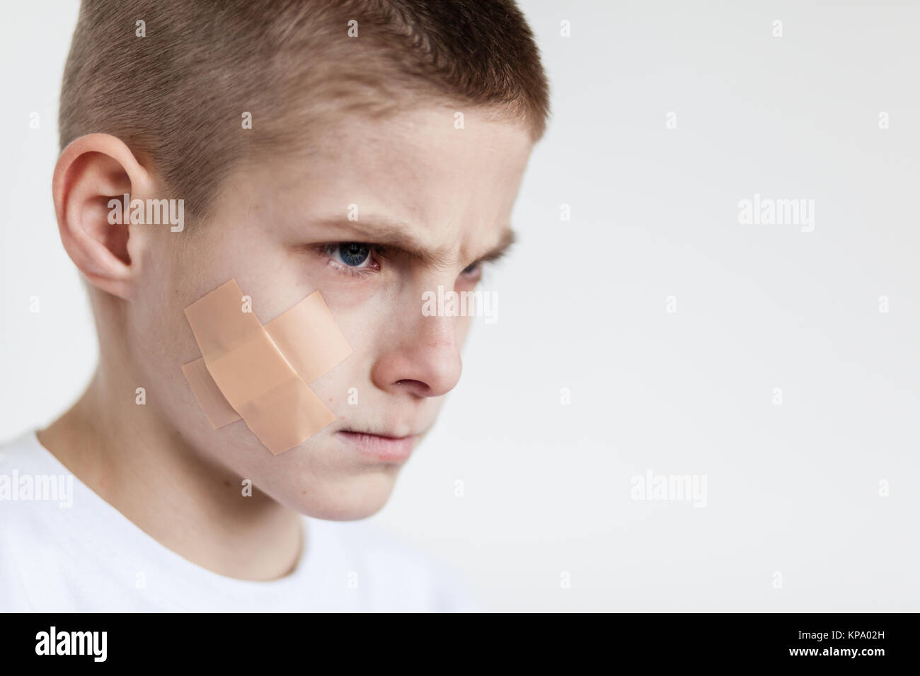 Angry Boy with Bandage on Face Looking to Distance Stock Photo