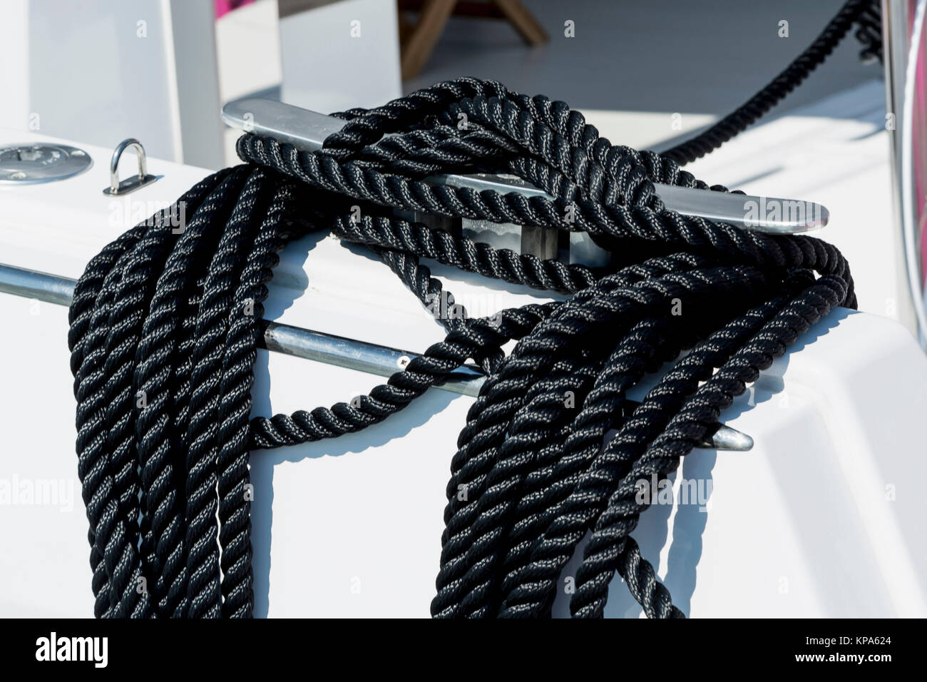 Closeup of a mooring rope with a knotted end tied around a cleat on a