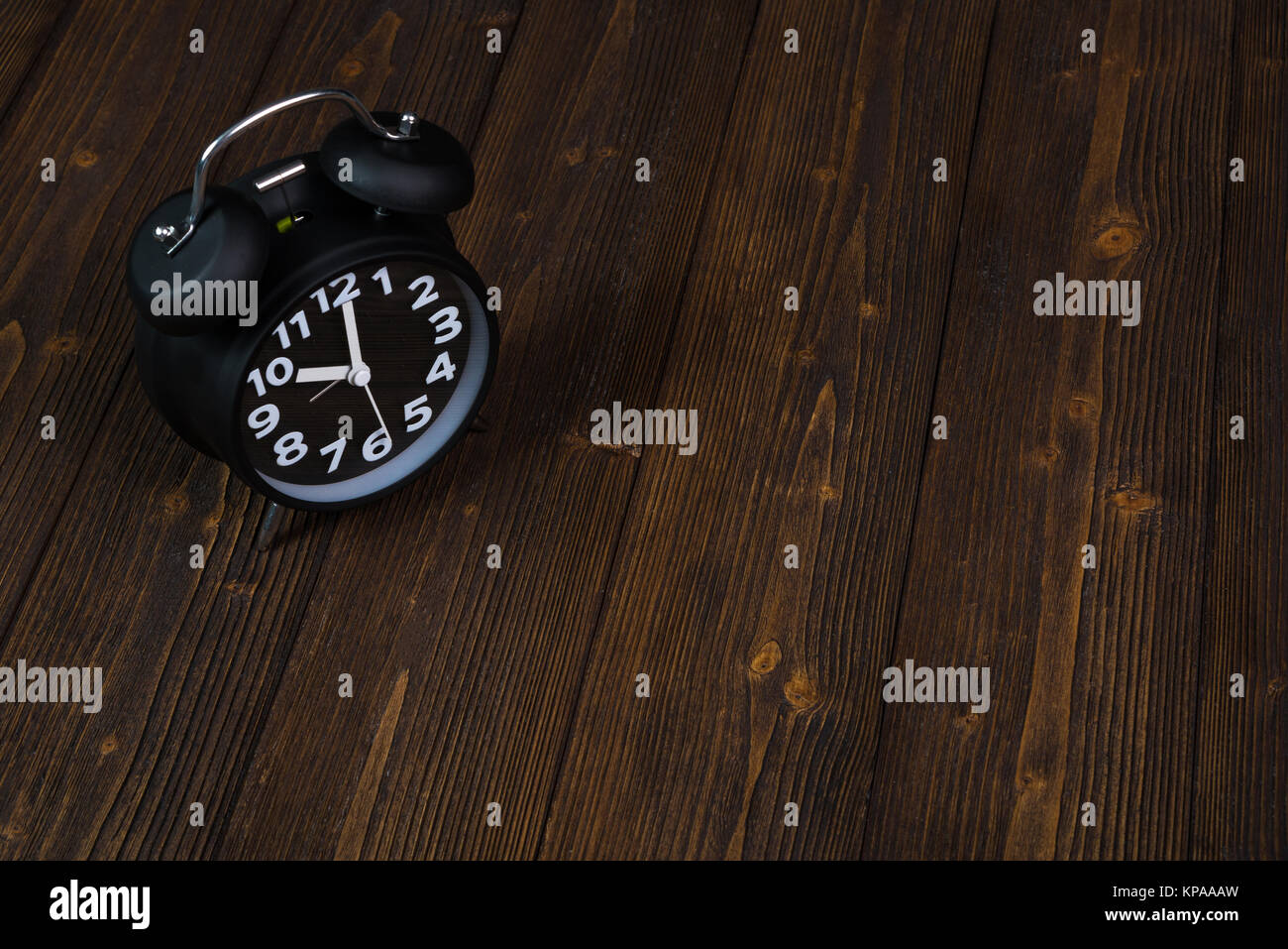 Vintage black alarm clock on dark wood table, time and deadline concept