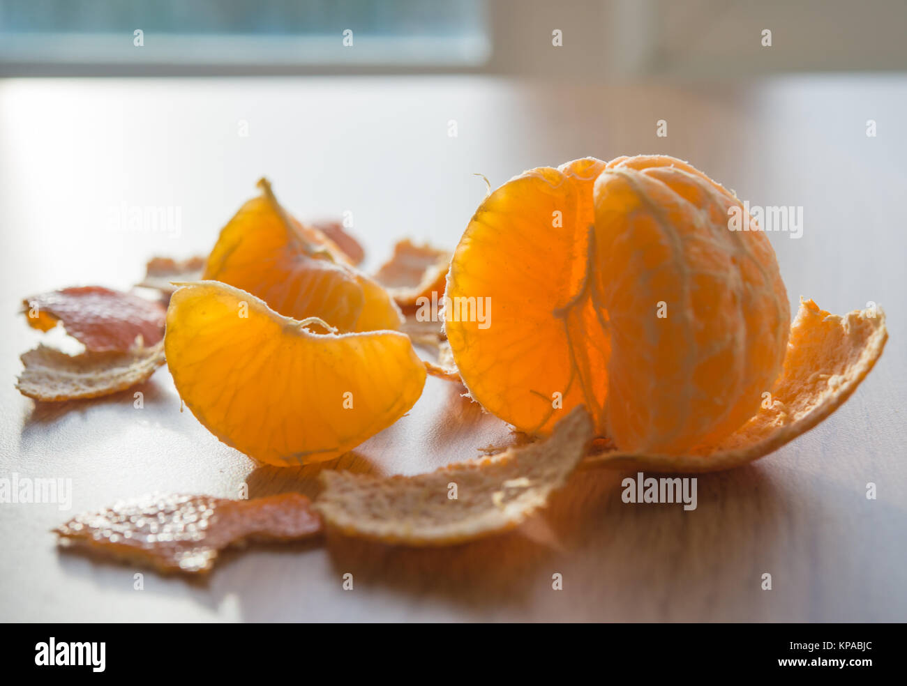 Peeled tangerine and segment backlit from the sun Stock Photo