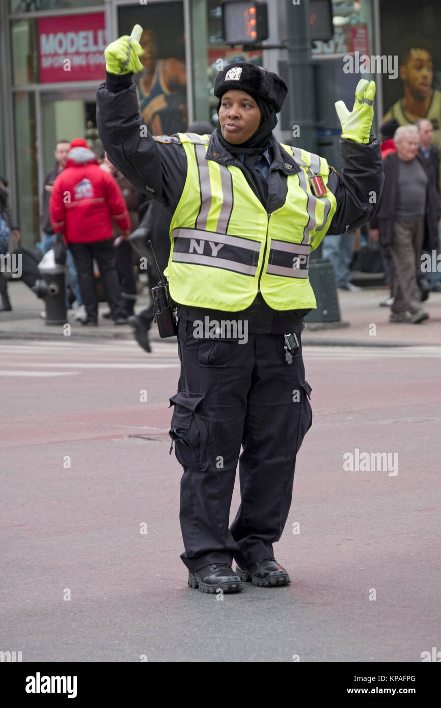 An African American policewoman directing traffic & gesturing on West 34th Street and 8th Avenue in Manhattan, NYC Stock Photo