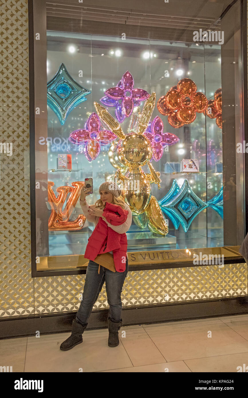 A beautiful American tourist takes a selfie in front of a Louis Vuitton display at Herlad Square in Manhattan, New York City. Stock Photo