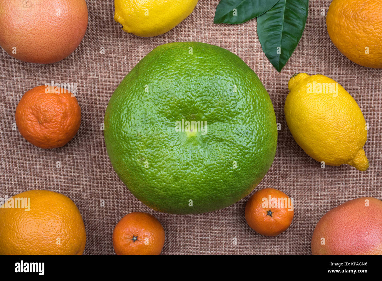 Top view on whole citrus fruits assortment on natural sacking material used as background. Assortment includes lemons, oranges, mandarins or tangerine Stock Photo