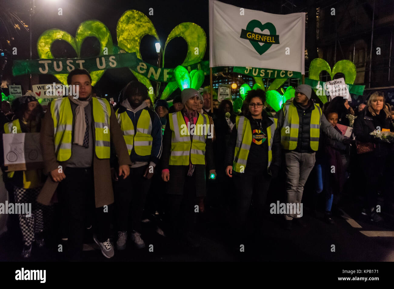 December 14, 2017 - London, UK. 14th December 2017. The monthly slow and silent walk to demand justice and remember those killed at Grenfell Tower starts from Notting Hill Methodist Church on the 6 month anniversary of the tragic fire. The families of those who died and survivors made homeless by the fire marched at the front, together with local clergy. Many carried pictures of the victims and flowers, as well as green lights and green heart-shaped symbols. Placards and posters called for Justice for Grenfell, which many fear the official inquiry will fail to provide. I left the procession a Stock Photo