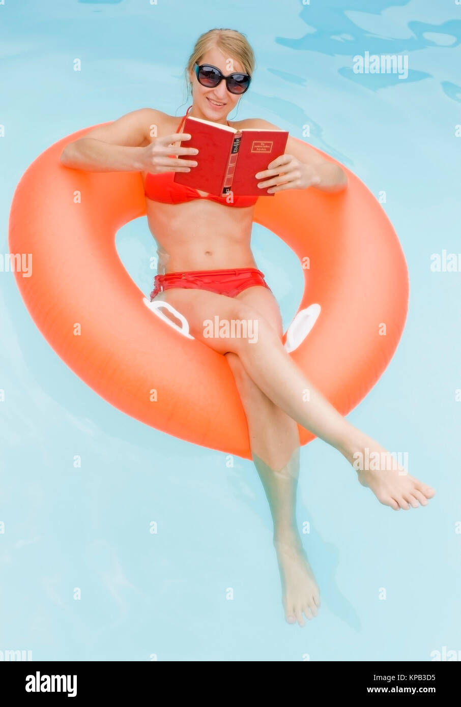 Model release, Junge Frau im Bikini beim Lesen im Swimmingpool - woman reading in swimming pool Stock Photo