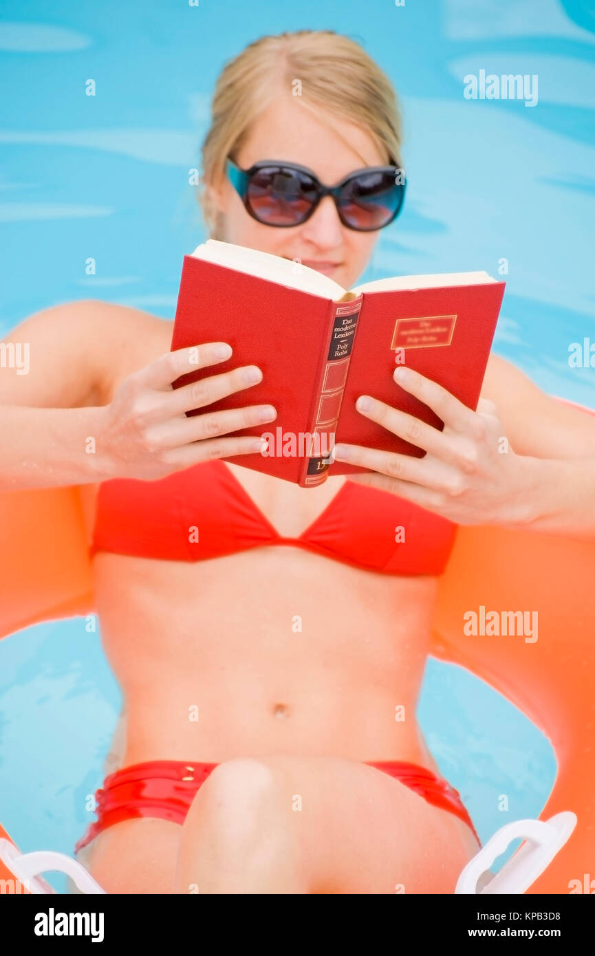 Model release, Junge Frau beim Lesen im Swimmingpool - woman reading in swimming pool Stock Photo