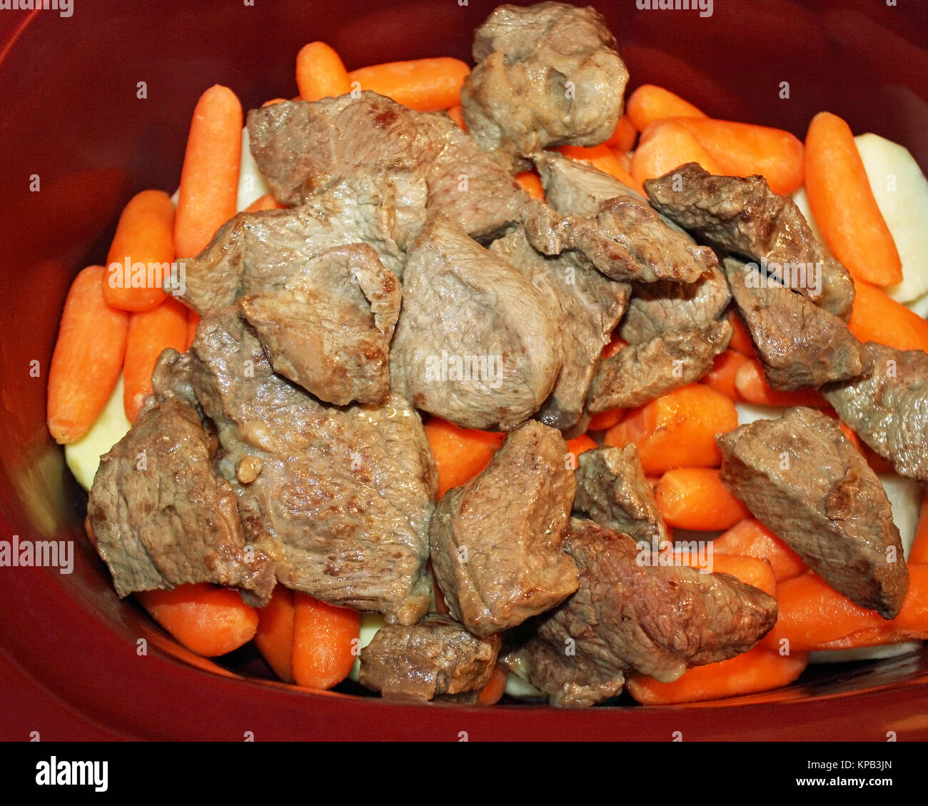 Layers of sliced white potatoes, peeled mini baby carrots and browned