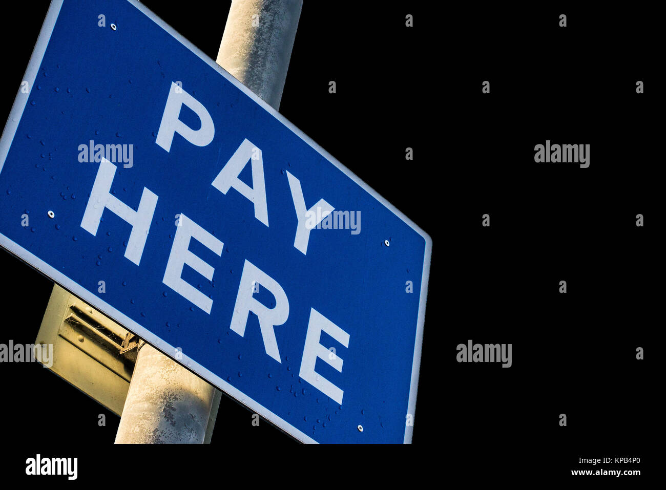 Car Park Pay Here Sign on a Pole on a Black Background With Copy Space Stock Photo