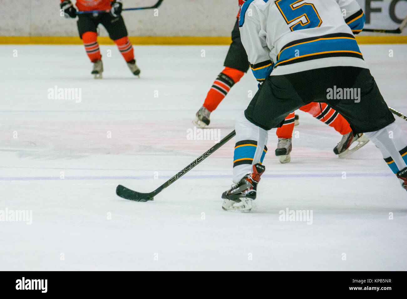 Closeup image of hockey players' legs and feet in red and black uniform