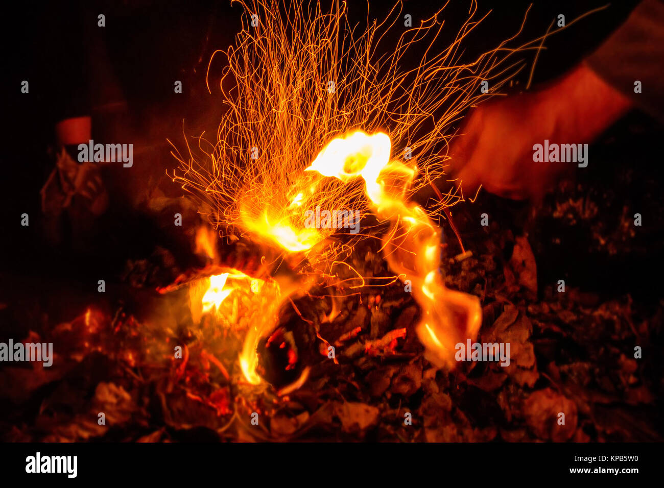 Close up picture of man's hand touching fire with stick taken with slow