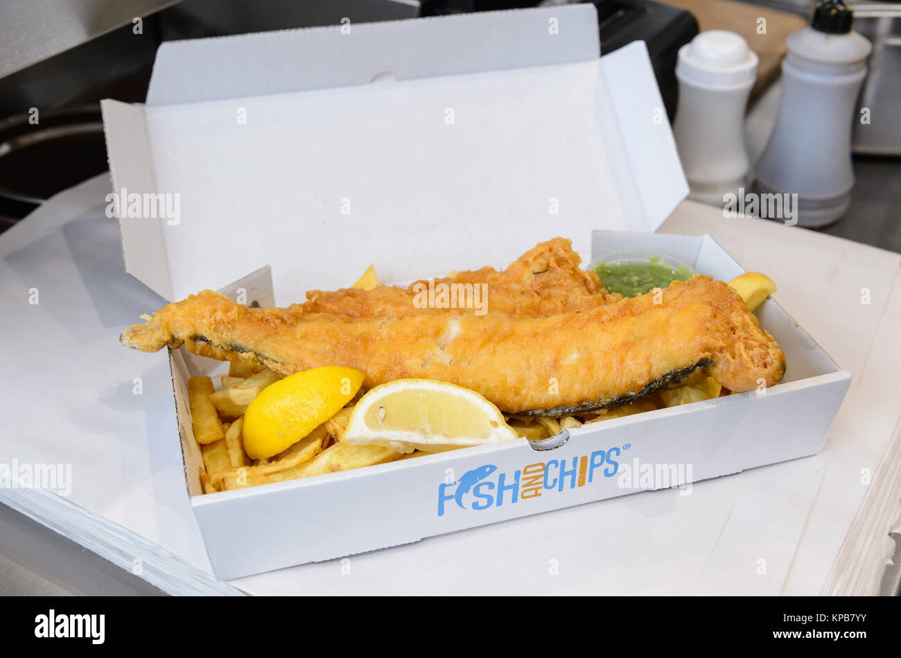 A large portion of traditional British fish and chips with mushy peas in a box. Stock Photo