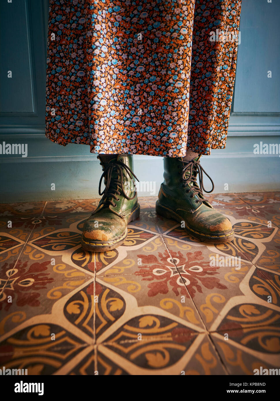 Wearing worn green Dr Martens boots / shoes with a skirt in a rustic style french house interior - work boots - odd - quirky style Stock Photo