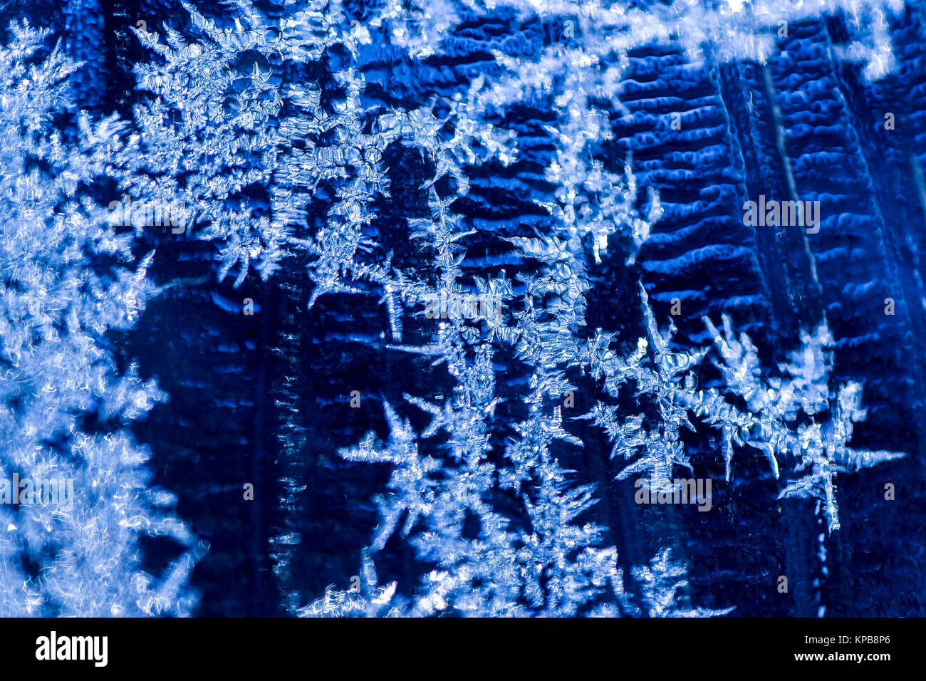 Ice crystals formed on window against a cold blue background Stock Photo