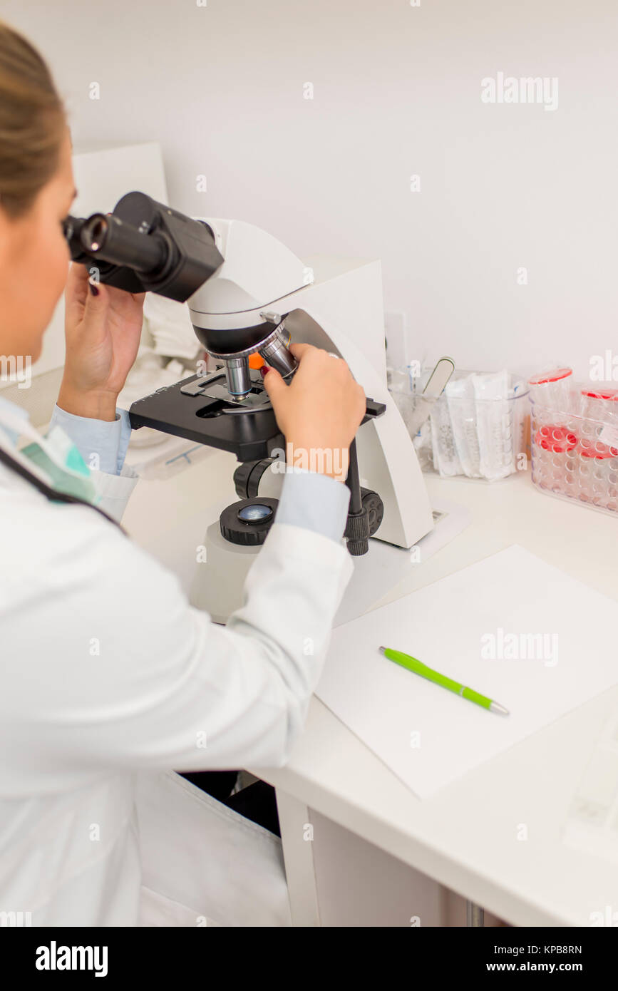 Focused female science student looking in a microscope in a modern ...