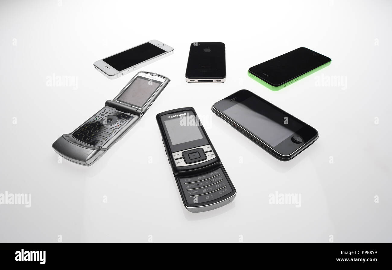 A mix of old mobile phones including iPhone, Motorola and Samsung on a white background. Stock Photo