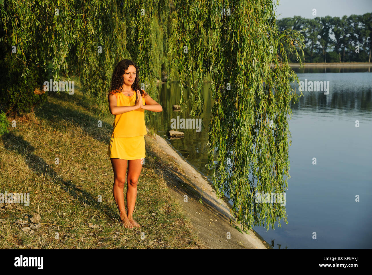 Beautiful young woman performing yoga exercises on the lake Stock Photo ...