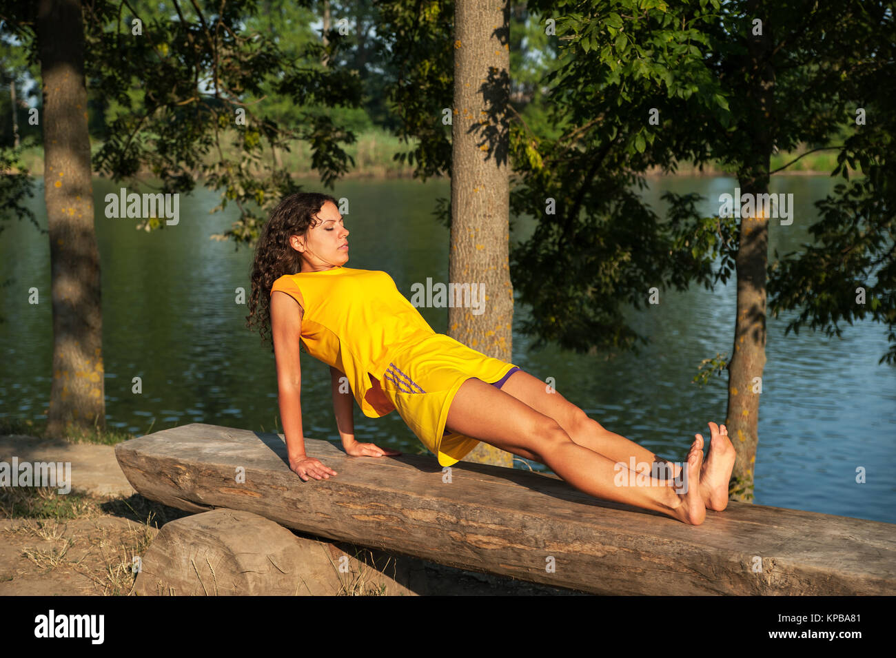Beautiful young woman performing yoga exercises on the lake Stock Photo ...
