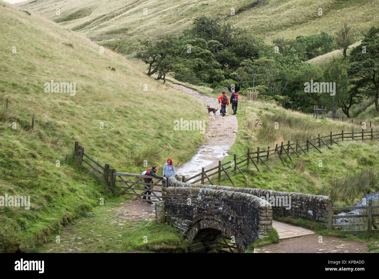 People walking in the countryside near the stone bridge over the River Noe, Vale of Edale, Derbyshire, Peak District National Park, England, UK Stock Photo