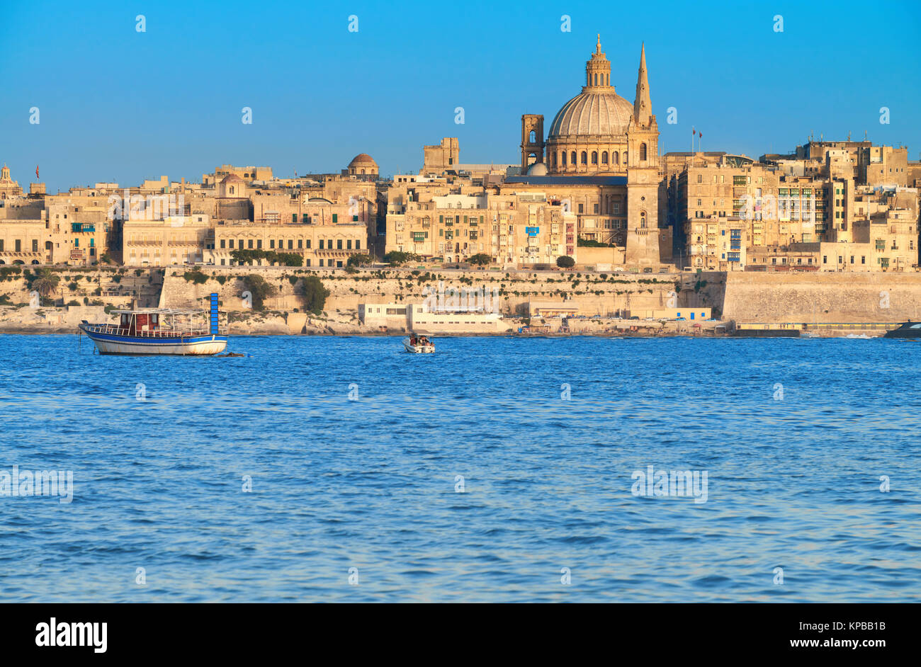 Malta, Valetta, cityscape. Touristic boat, ancient fortifications of La Valetta, old houses and St. Paul's Cathedral Stock Photo