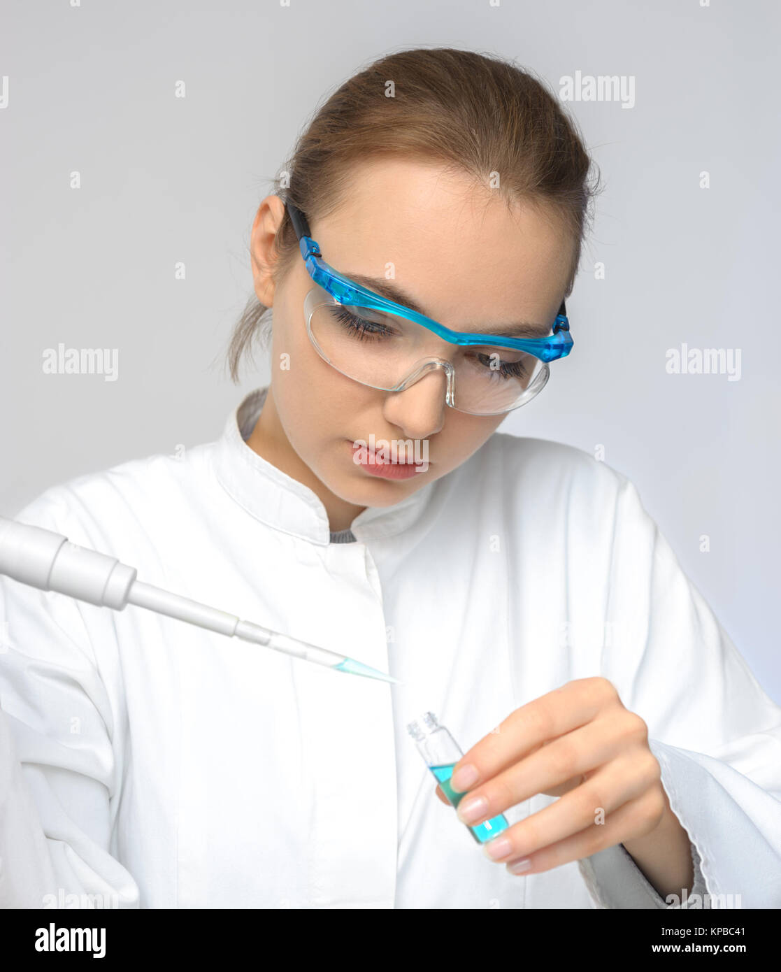 Young female tech or scientist loads sample with automatic pipette Stock Photo