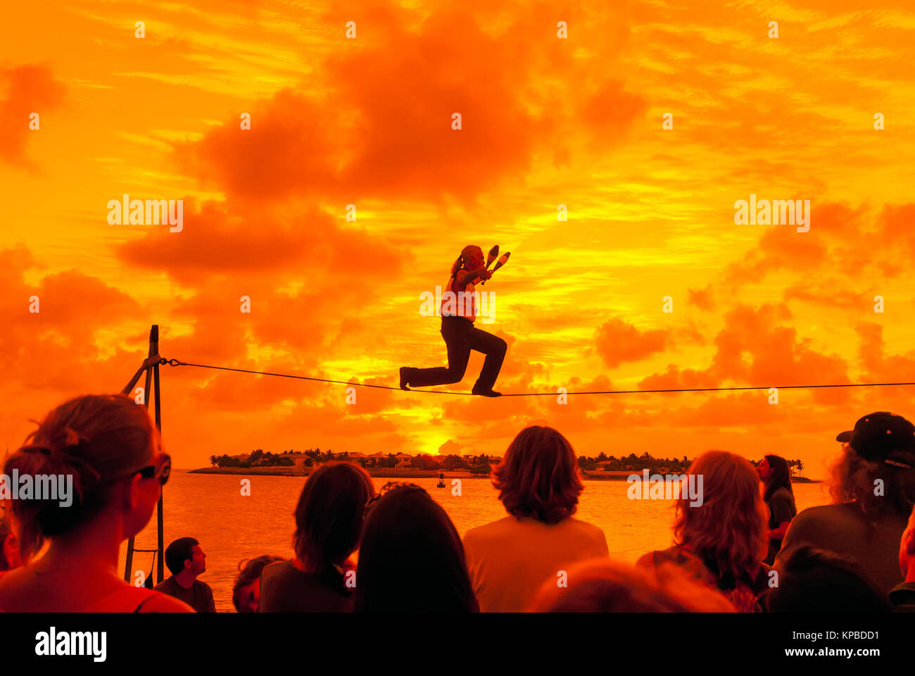 Tight Rope Walker at Key West Sunset Celebration in Mallory Square with bright orange sunset, Florida Stock Photo