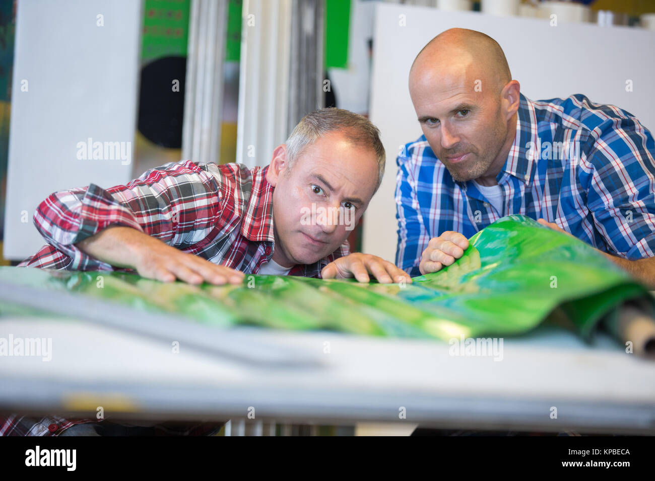 Men examining unrolled plastic product Stock Photo - Alamy