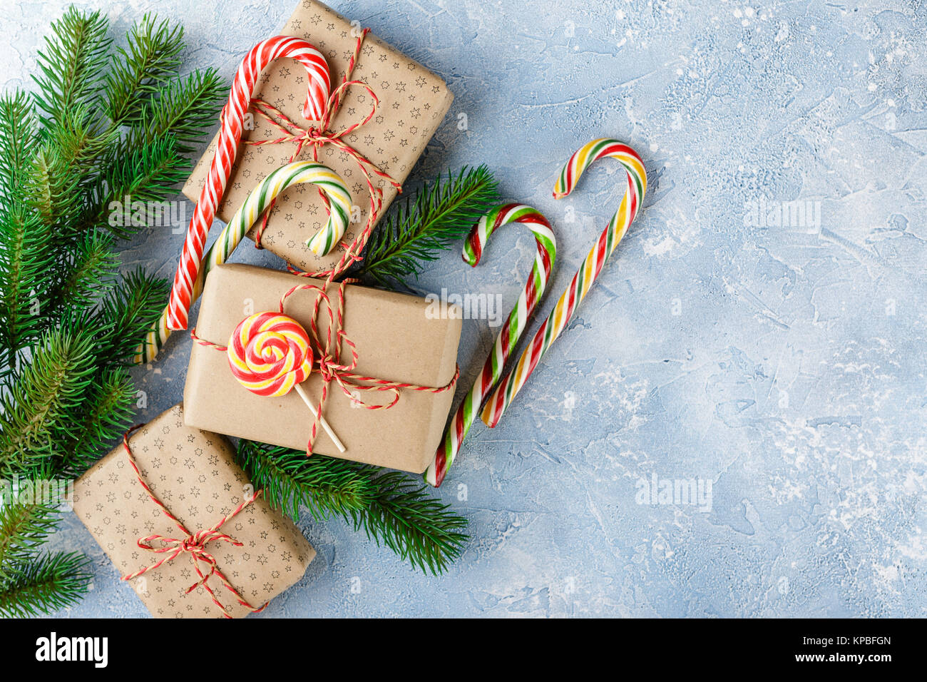 Gift boxes in kraft paper, candy canes and branch of Christmas trees on ...