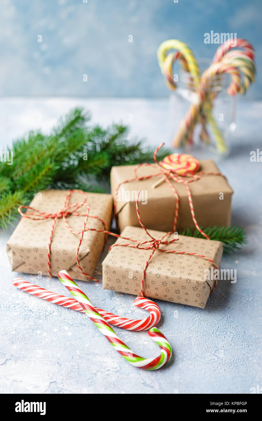 Gift boxes in kraft paper, candy canes and branch of Christmas trees on ...