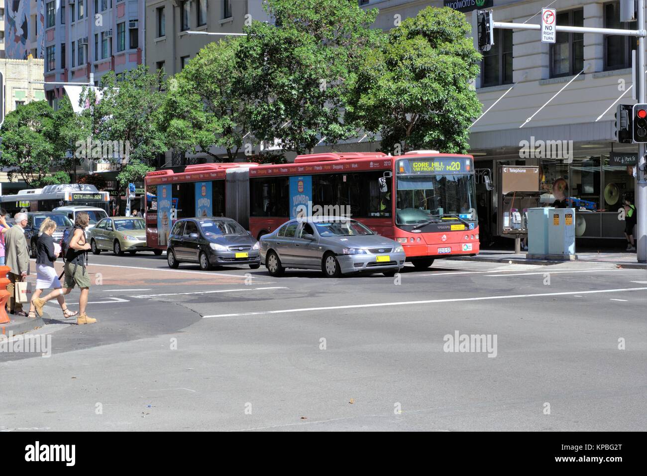 Sydney street day time. Traffic intersection in Sydney Australia. Pedestrians crossing street at a traffic crossing while vehicles wait. Stock Photo