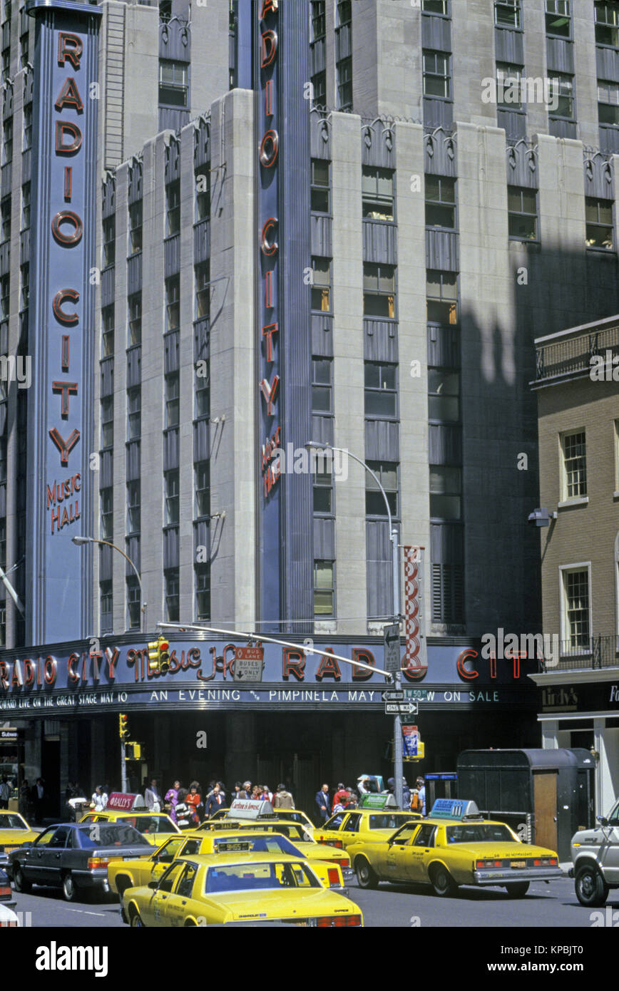 1987 HISTORICAL YELLOW TAXI CABS (©GENERAL MOTORS 1985) RADIO CITY MUSIC HALL ROCKEFELLER CENTER (©RAYMOND HOOD 1939) SIXTH AVENUE MANHATTAN NEW YORK CITY USA Stock Photo