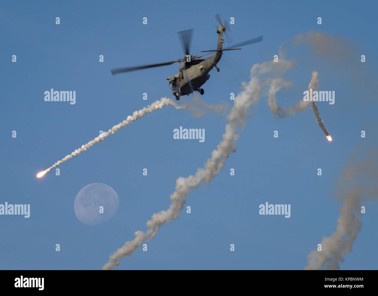 A U.S. Navy MH-60S Seahawk helicopter fires celebratory flares over the U.S. Navy Nimitz-class aircraft carrier USS Theodore Roosevelt during a change-of-command ceremony December 6, 2017 in the Arabian Gulf. Stock Photo