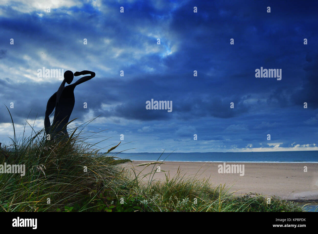 Statue of man looking out to sea in Dingle, Ireland. Moody, cloudy sky