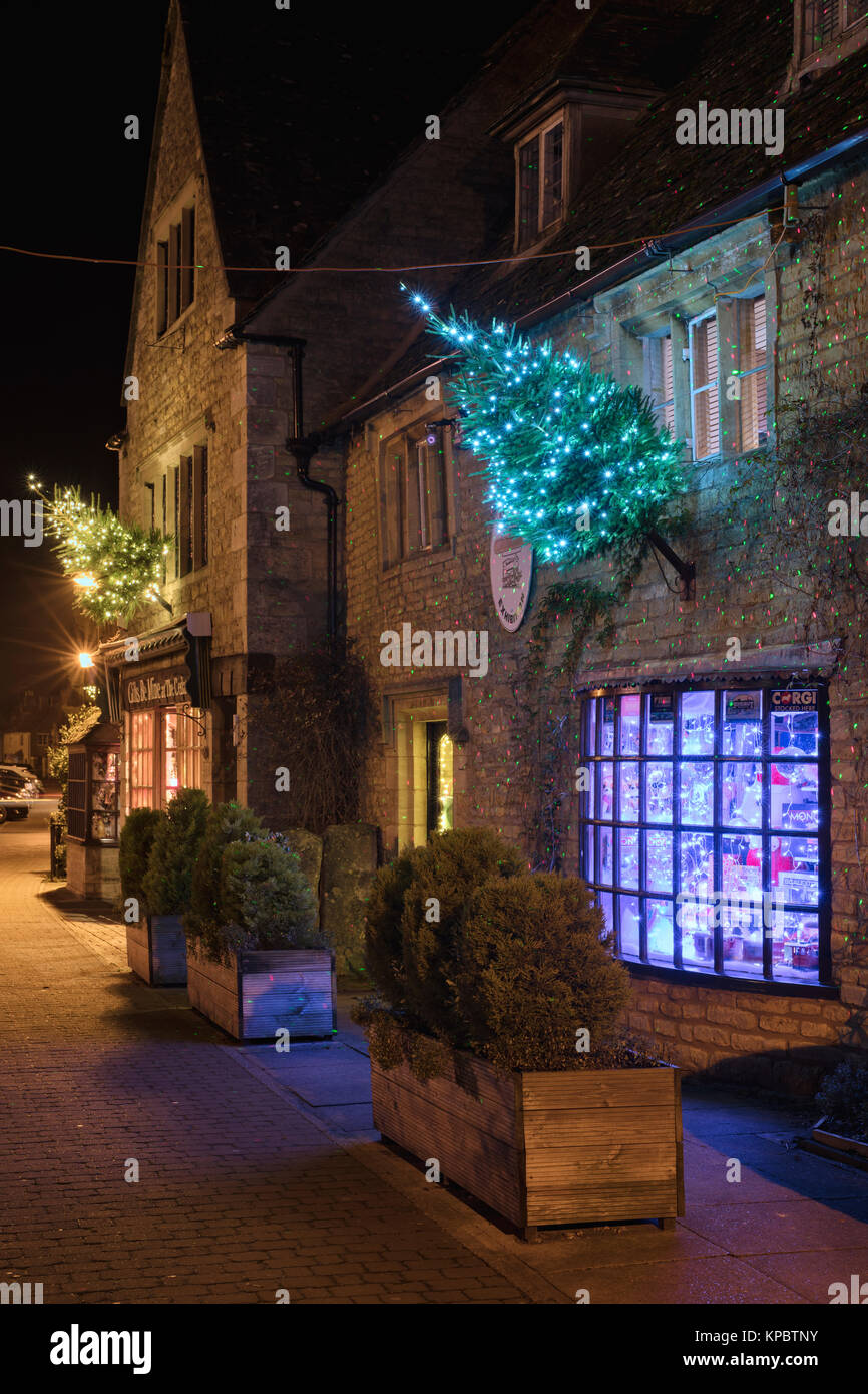 Bourton on the Water shops with christmas trees and lights along the high street at night