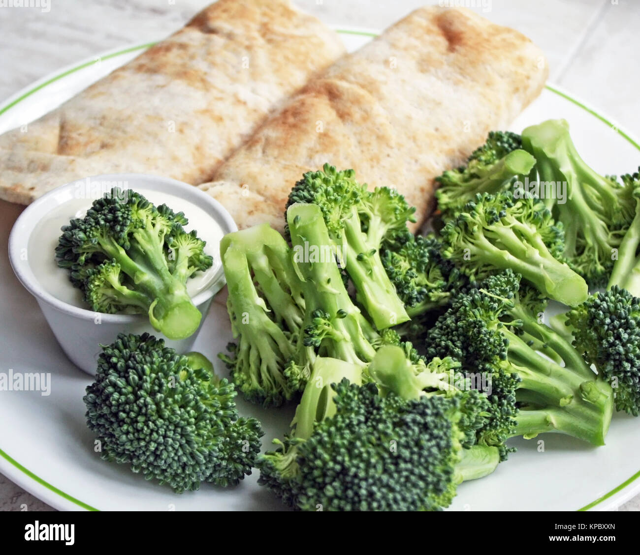 Two filled Tortilla wraps with a side of fresh broccoli and a container of creamy dressing for dipping Stock Photo