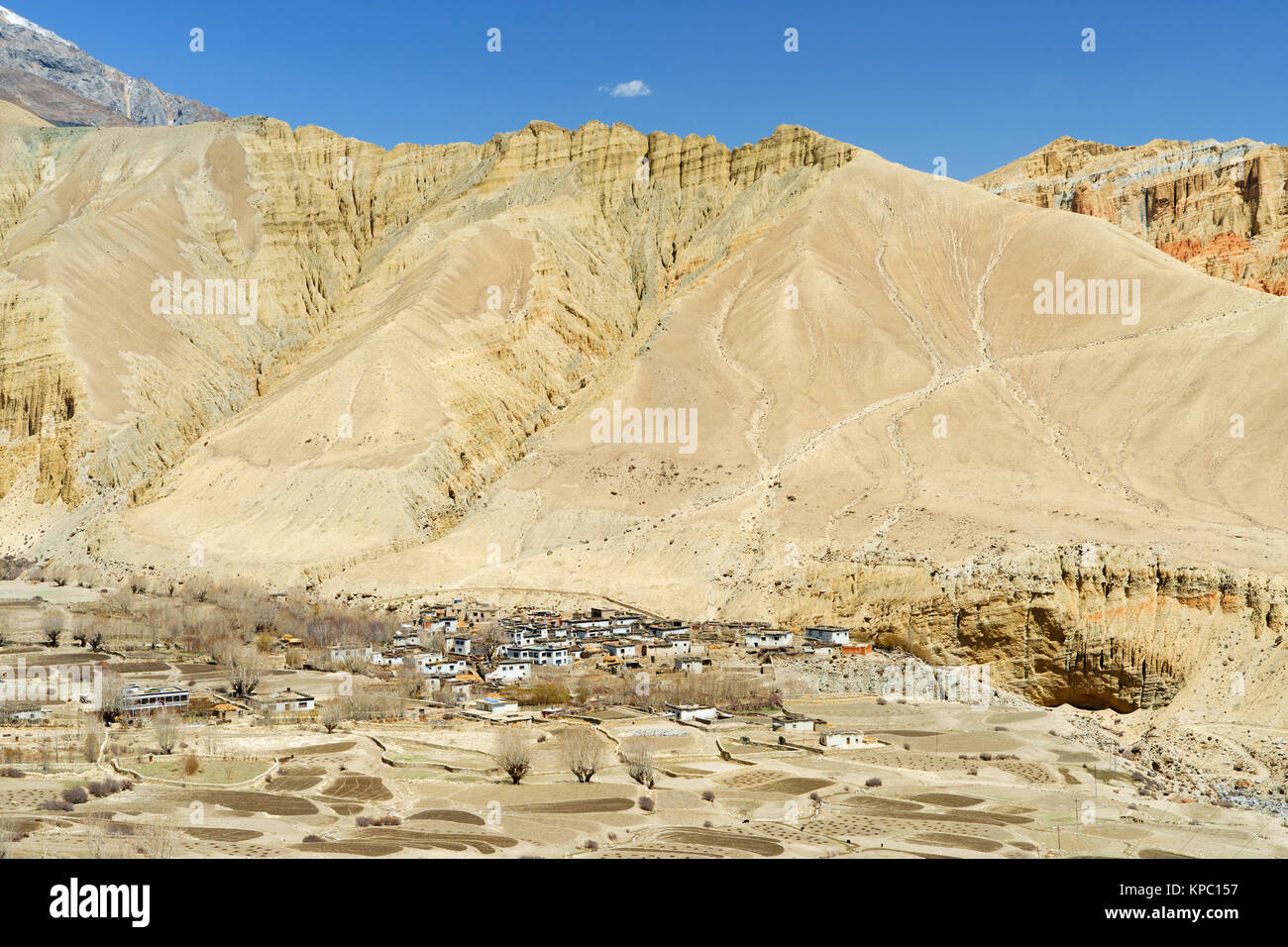 Village of Ghemi, Upper Mustang region, Nepal, viewed from a distance amidst a barren desertic landscape. Stock Photo