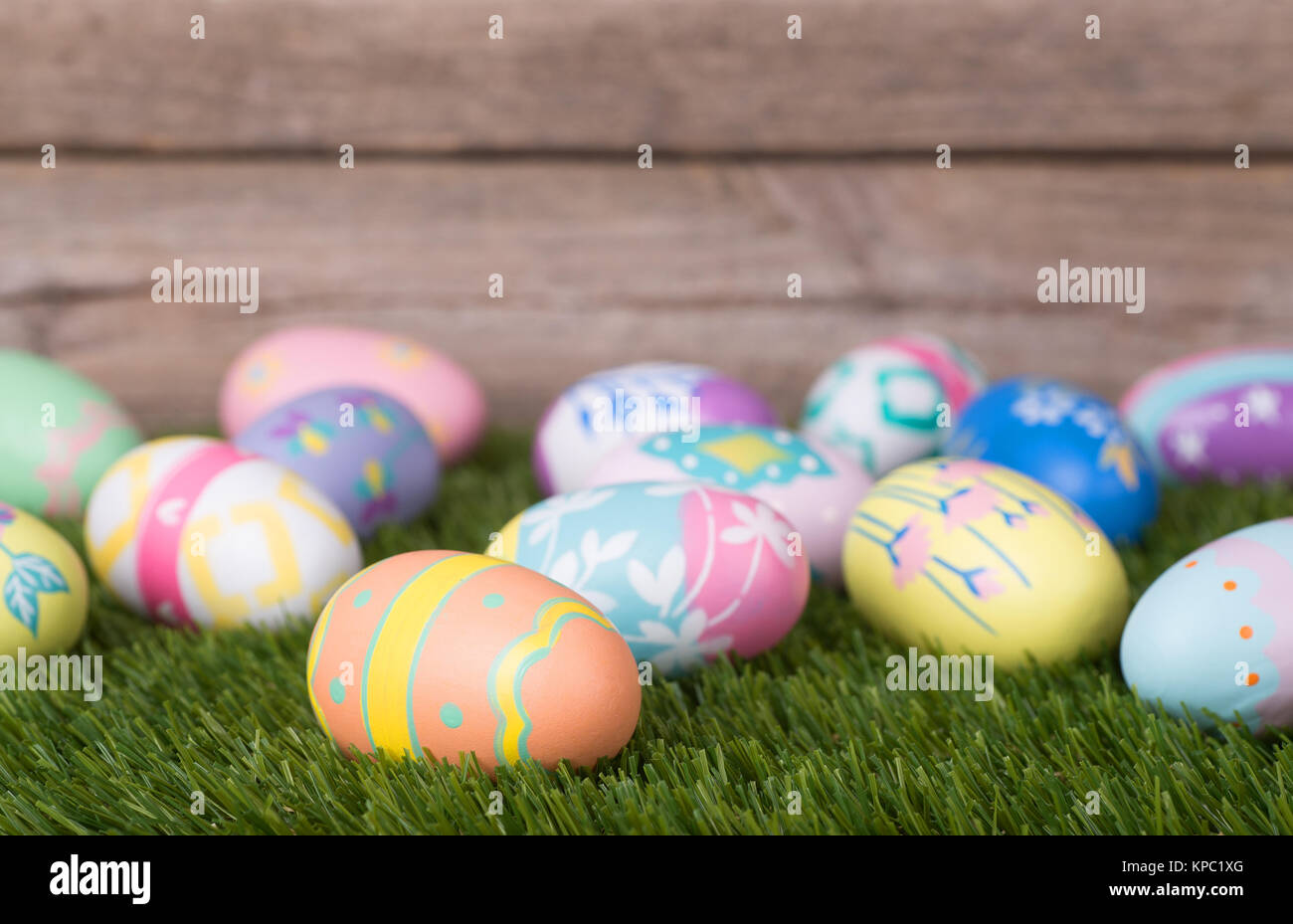 Colorful Easter eggs on grass against a wood background Stock Photo - Alamy