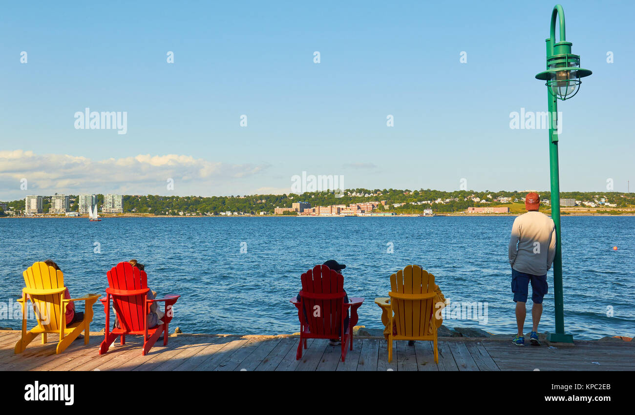 Tourists relaxing at water's edge on Halifax waterfront boardwalk, Halifax, Nova Scotia, Canada Stock Photo