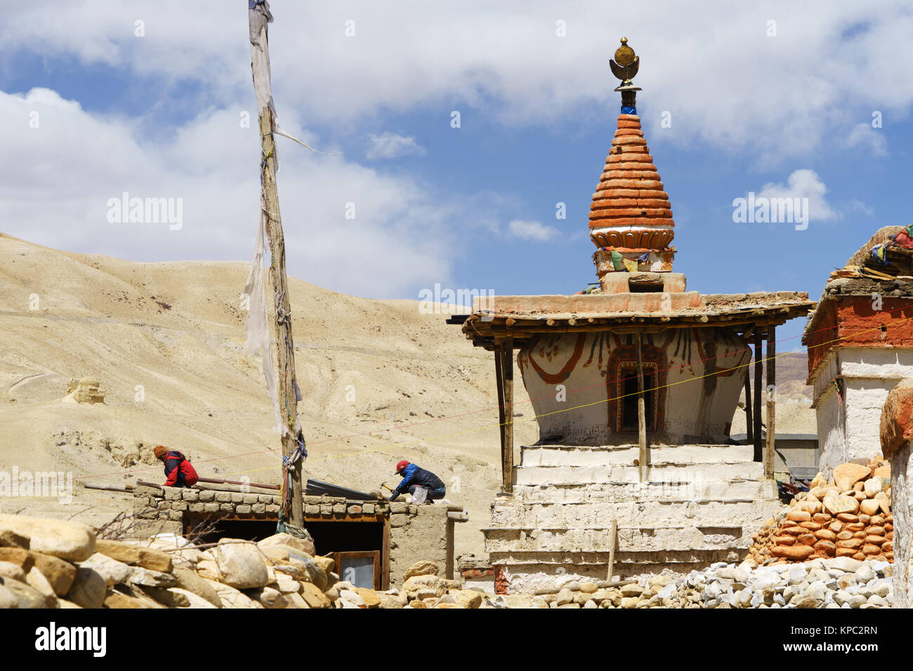 Two Tibetan men are repairing a shed adjacent to a Buddhist stupa in Lo Manthang, Upper Mustang region, Nepal. Stock Photo