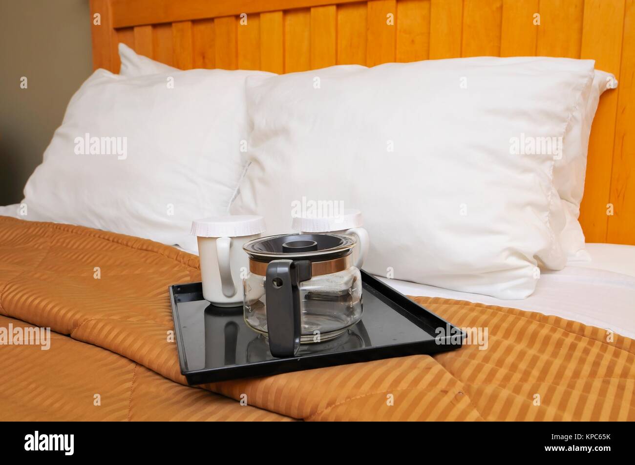 Coffee or tea maker and cups on bed for relaxed breakfast. Stock Photo