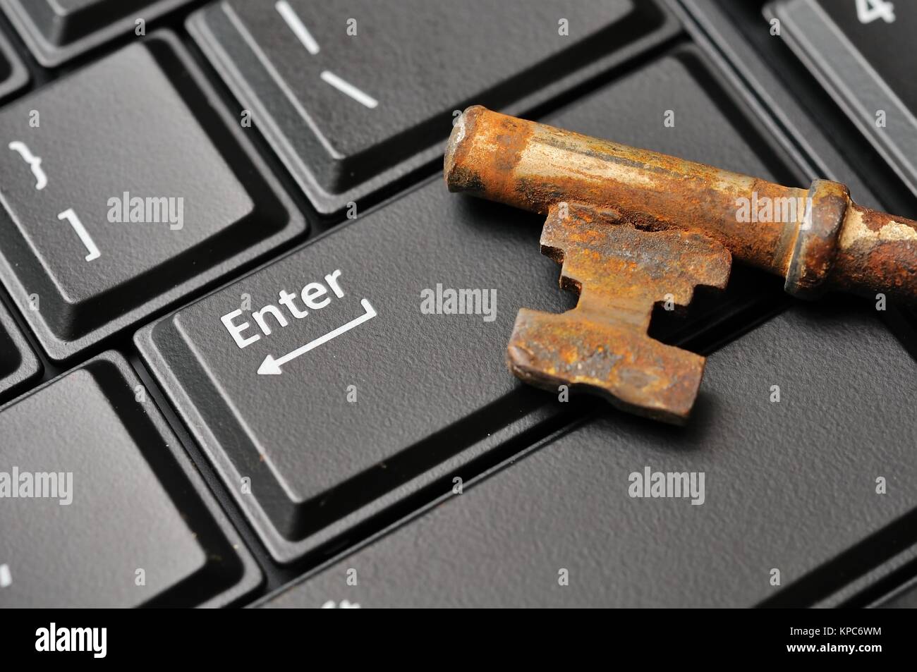 Macro shot of antique rusty key on black Enter computer key. Stock Photo